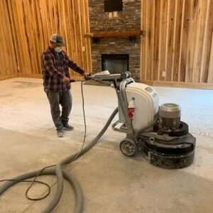 Worker polishing concrete floor with industrial grinder 